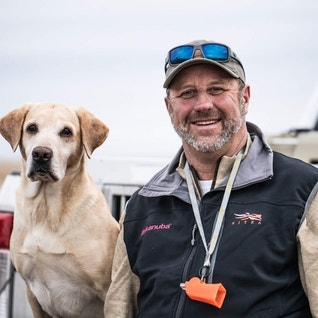 Chris Akin with his yellow Lab sitting on a tailgate