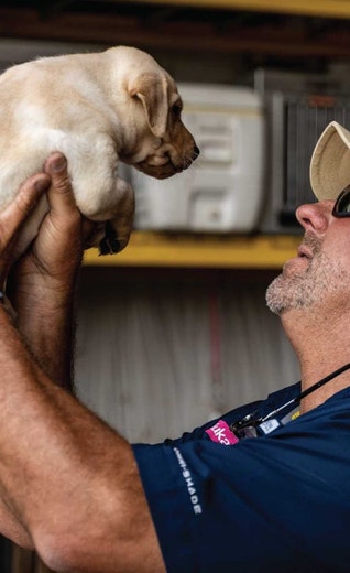 /au/sites/g/files/fnmzdf6461/files/2024-08/us-esd-eukanuba-pro-trainer-chris-akin-holds-a-lab-puppy.jpeg