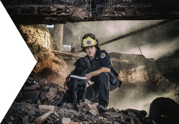 Fireman standing behind a black dog in a burnt building