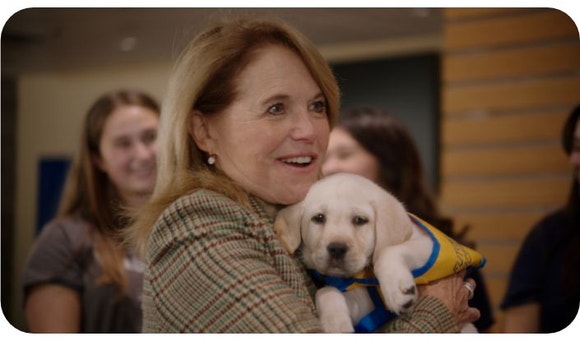 katie couric holding a canine companions puppy